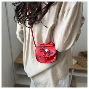 Detail van rode leren crossbodytas met strikdecoratie en pony-borduurwerk op model