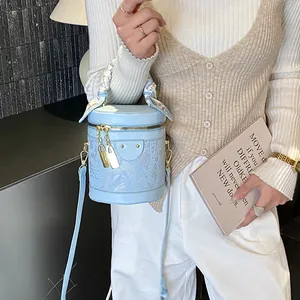 Borsa a secchiello azzurra cilindrica con pizzo e foulard in seta su modella