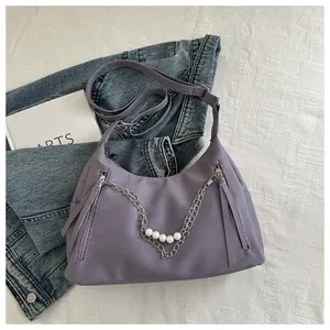 Detalle de bolso de mano media luna morado con cadenas de plata y perlas finas