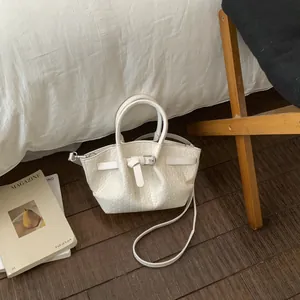 Detailed view of white woven texture and belt buckle on a luxury synthetic leather bucket bag