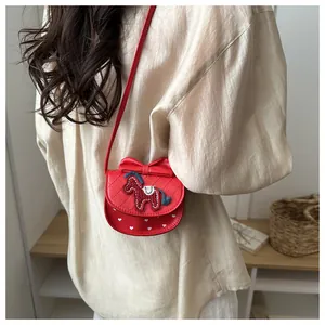 Detail van de rode crossbodytas met strik, ponyborduurwerk en hartjespatroon