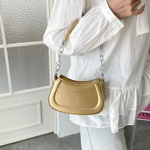 Metallische goldene Halbmond-Tasche mit Kettenriemen am Model gezeigt
