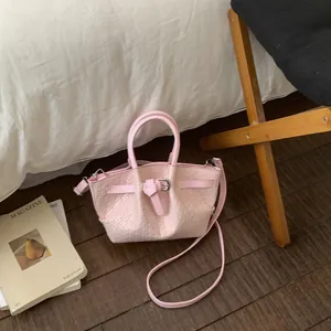 Detail of pink woven bucket bag with smooth handles and silver metal hardware