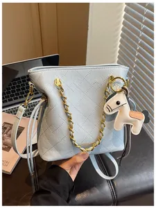 Close-up of light blue quilted bucket bag with gold chain and horse charm detail
