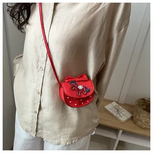 Detail van rode gewatteerde crossbodytas met strikversiering en paardenborduurwerk