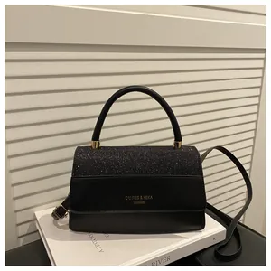 Detail of elegant black crossbody bag with sequin patchwork and gold brand lettering