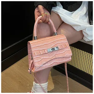 Detail of pink faux crocodile texture handbag with silver twist lock and slim strap