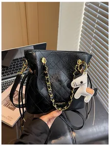 Detail of black quilted bucket bag featuring gold chain strap and pony charm accent