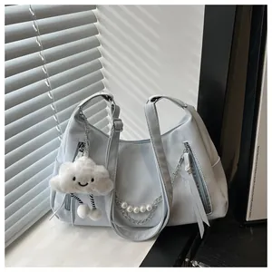 Detalle de bolso azul claro con cadena de perlas y colgante de nube sonriente