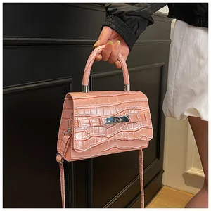 Detail shot of the pink croc-embossed texture and silver metal lock on a small handbag