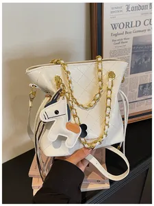 Close-up of white quilted bucket bag with gold chain and horse charm detail