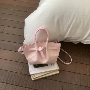 Detail of light pink woven texture bucket bag with silver buckles in a lifestyle setting
