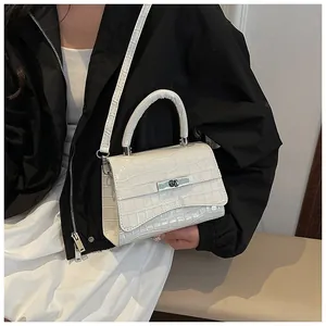 Detail of white crocodile pattern handbag with silver metal twist lock and shoulder strap