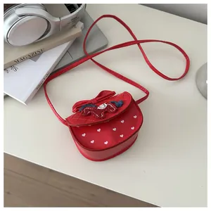 Detail van rode crossbodytas met hartjesprint en cartoonpaardborduurwerk