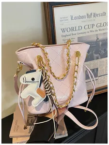 Detailed shot of pink quilted bucket bag featuring a gold chain and white horse charm