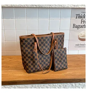 Close-up of retro brown monogram tote bag set with matching zipper pouch on wooden table
