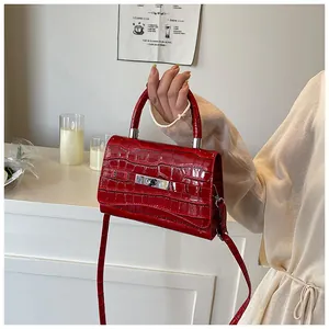 Close-up of red crocodile-pattern leather bag with silver twist-lock and top handle