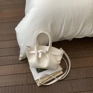 Top view of cream white woven bucket bag with leather strap on a stylish background
