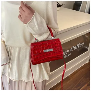 Model wearing orange croc-embossed handbag with silver buckle and crossbody strap