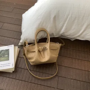 Top-down view of light brown woven texture bucket bag on wooden floor with magazine