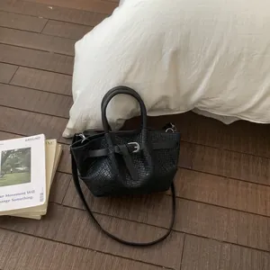 Top view of black woven bucket bag with silver buckle on a wooden floor