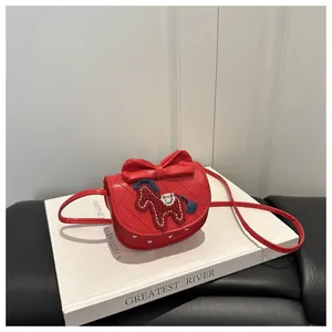 Detail van rode gewatteerde PU-leren handtas met strik en borduursel op een wit boek