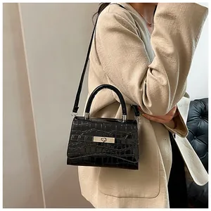 Close-up of black crocodile pattern handbag with silver clasp on beige blazer