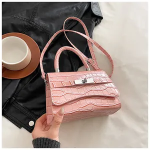 Detail of pink faux crocodile leather handbag featuring a silver twist lock and carry handle