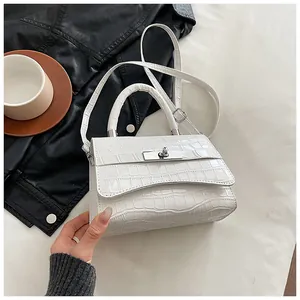 Close-up of white croc-embossed trapezoid handbag with silver twist lock and strap