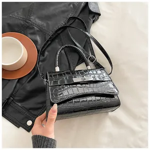 Detailed view of black crocodile pattern faux leather handbag with silver metal turn-lock