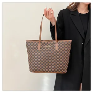 Detail of the monogram M pattern and gold brand logo on the brown leather tote bag