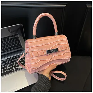 Detail of pink croc-embossed small handbag with silver metal lock and top handle