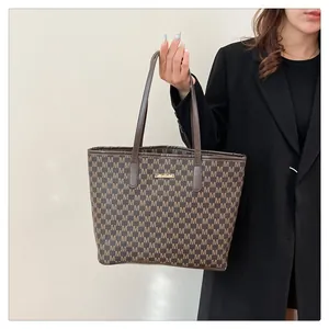 Detail of deep brown tote bag with M letter prints and gold metallic logo plaque