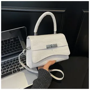Close-up of white crocodile embossed leather bag with silver metal lock and top handle