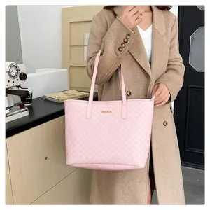 Close-up of pink tote bag with M-letter pattern and golden metal logo plate