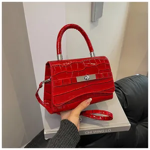 Detail of red crocodile pattern handbag with silver hardware clasp and top handle