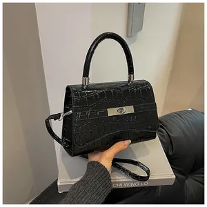 Detail shot of black crocodile texture handbag with silver metal twist lock closure