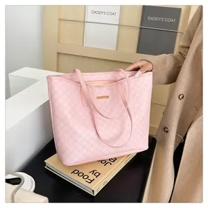 Close-up of pink tote bag featuring monogram pattern and gold metal logo plaque
