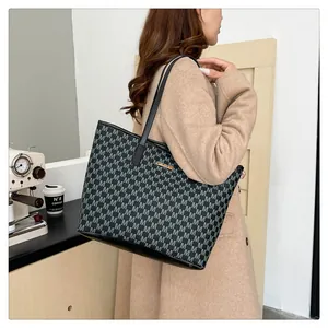 Close-up of stylish grey tote bag with letter pattern and gold logo in cafe setting