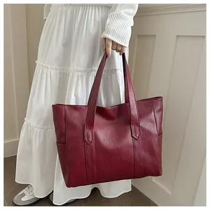 Nahaufnahme der weinroten Shopper-Tasche mit Lychee-Struktur und langen Schulterriemen