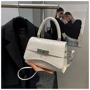 Close-up of white crocodile pattern handbag with silver metal lock and curved base