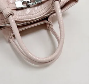 Dettaglio della borsa a secchiello rosa chiaro con trama lucida e fibbia argento