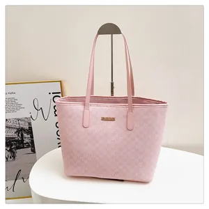 Detail of pink tote bag showing M-letter monogram pattern and gold metal logo plaque