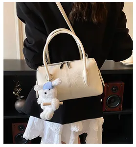 Detail of off-white lychee texture Boston bag with a cute plush bunny charm and silver zipper