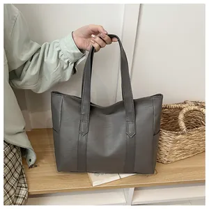 Detail der dunkelgrauen PU-Shopper-Tasche mit langen Griffen auf einem rustikalen Holzregal