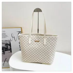 Detail of monogram tote bag with golden logo plate on a stylish display stand