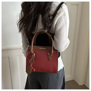 Détail d'un sac cabas rouge et marron avec pendentif cerise et texte FASHION & BAGS