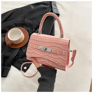 Detail of pink croc-effect small square bag featuring a silver metal twist lock closure