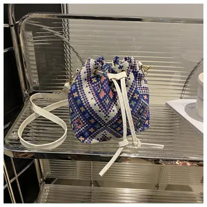 Detailed view of bohemian geometric pattern on drawstring bucket bag with white leather strap