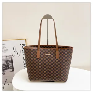 Macro shot of brown monogram tote bag with golden logo plaque and leather handles